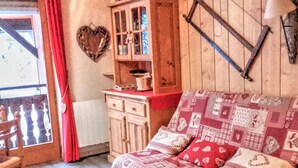 A cozy room with a wooden sofa, a heart-shaped decoration on the wall, and a wooden cabinet with glass doors. - Renovated studio by the cable car, parking, WiFi (Morzine)
