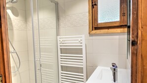 A bathroom with a glass shower enclosure, a white towel rack, and a wooden cabinet above a sink. - Unique chalet near Morzine center with private garden and WiFi, sleeps 5 (Morzine)
