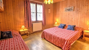 A wooden room with two beds, a window with curtains, a radiator, and a wall-mounted picture. - Unique chalet near Morzine center with private garden and WiFi, sleeps 5 (Morzine)