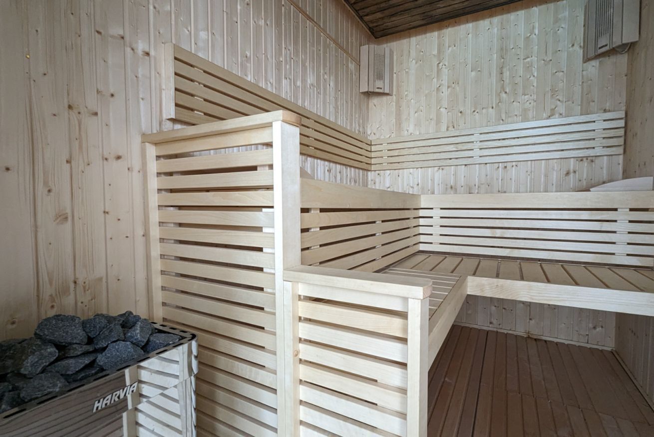 A sauna room with wooden benches and a stone container.