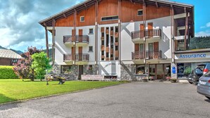Un edificio a due piani con balconi in legno, una insegna con scritto 'Assurance' a destra e una con 'Restoence of Tourism Studios Appartements' a sinistra.