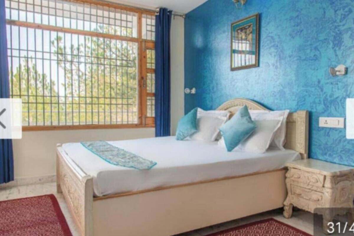 Ein Schlafzimmer mit einem Bett, einem Nachttisch, einem Fenster mit Gitterstäben und einer blauen Wand.
