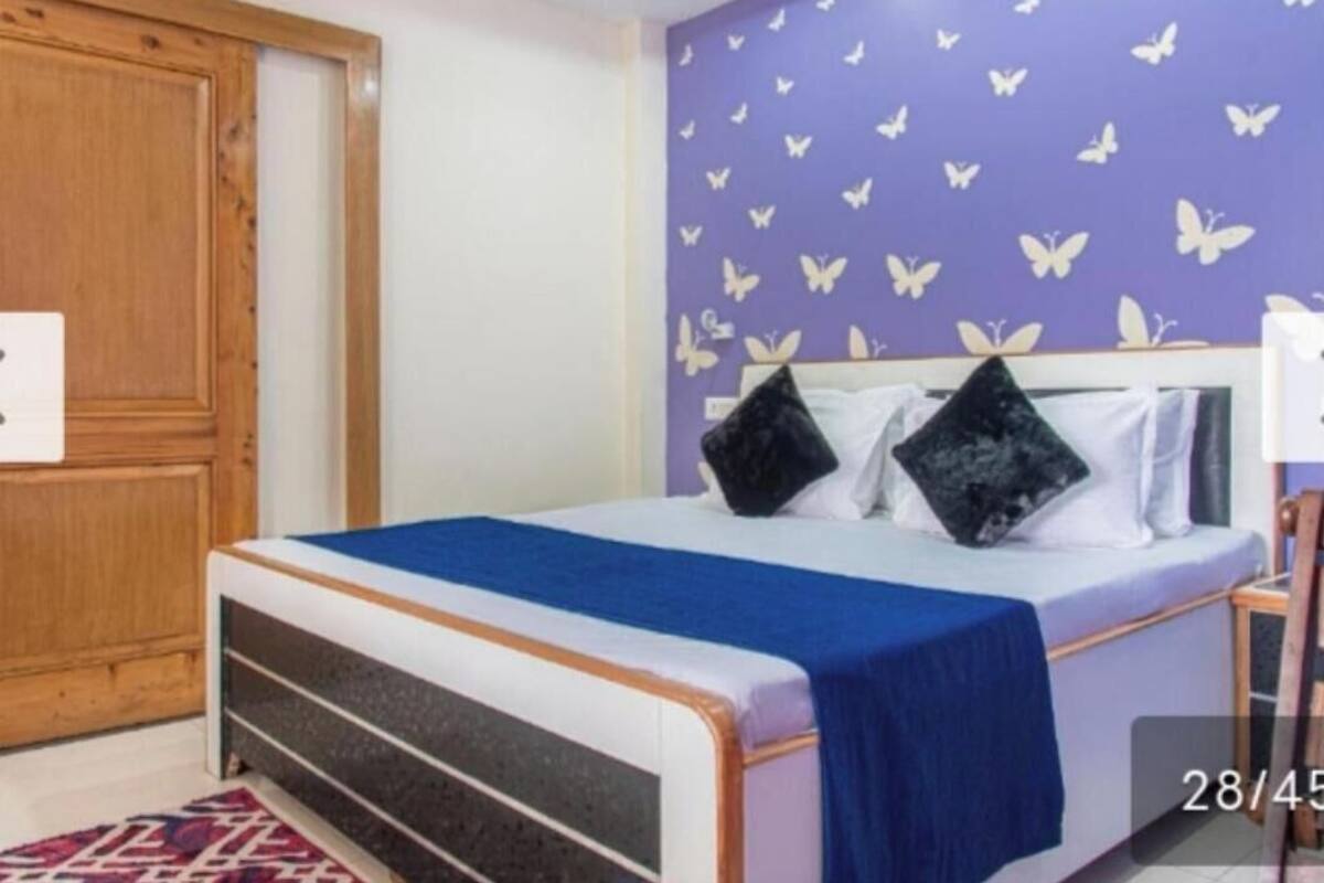 Ein Schlafzimmer mit einem Bett, einem Holzschrank und einer Wand mit einem violetten Schmetterlingsmotiv.
