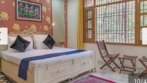 A bedroom with a bed, a chair, and a window with bars. - JP Restaurant And Resort (Solan)