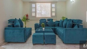 A living room with a sectional sofa, ottomans, and a small table. - JP Restaurant And Resort (Solan)