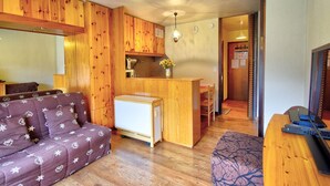 Een gezellige woonkamer met een bank, een kleine keukenhoek en een eethoek.