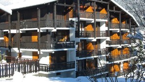 Een meerlaags houten gebouw met balkons, omringd door sneeuw.