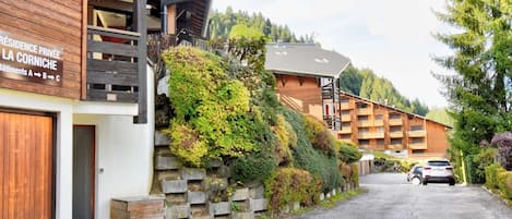 A multi-story building with a wooden facade and balconies. There is a sign indicating private residence and multiple buildings in the background.