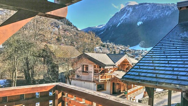 A wooden balcony with a view of a mountain and a village. - Studio in central Morzine with balcony and WIFI (Morzine)