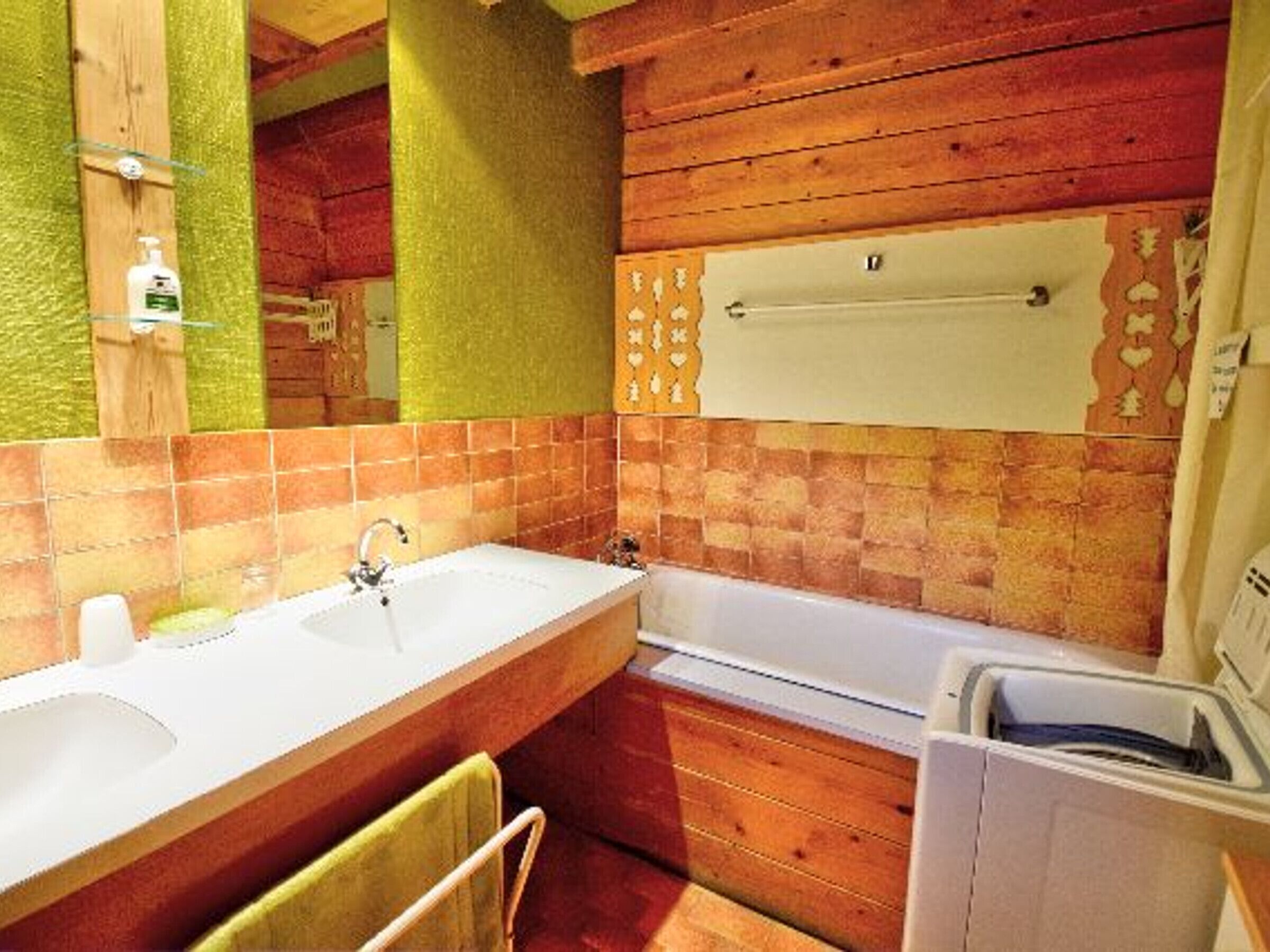 A bathroom with a wooden vanity, a sink, a bathtub, and a towel rack.