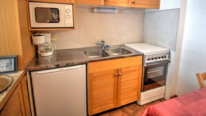 A compact kitchen with wooden cabinets, a microwave, a sink, a Bosch dishwasher, and a stove. - Studio with southwest-facing balcony, parking, pets allowed, 300m from center (Morzine)