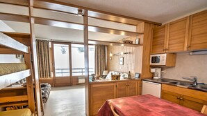 A compact room with bunk beds, a kitchenette, and a dining area. - Studio with southwest-facing balcony, parking, pets allowed, 300m from center (Morzine)