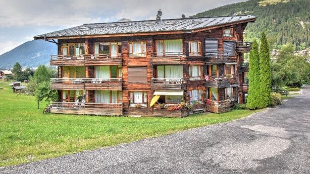 A multi-story wooden chalet with balconies, set in a mountainous area with a clear sky. - Studio with southwest-facing balcony, parking, pets allowed, 300m from center (Morzine)