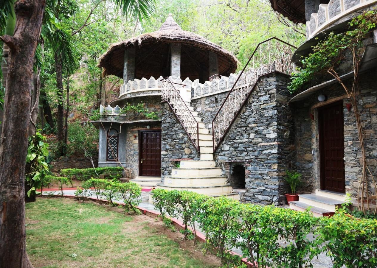 Un bâtiment en pierre doté d’une toiture en chaume, d’un escalier et d’un petit jardin.