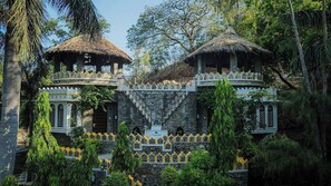 A traditional building with two thatched-roof structures, surrounded by lush greenery. - The Aodhi Kumbhalgarh (Kumbhalgarh)