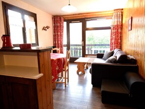 Relax in this inviting living area with a large window offering a view of the outdoors, a dining table, and a comfortable sofa.