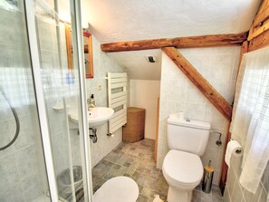 A bathroom with a shower, sink, toilet, and wooden beams.