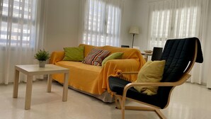 Uma sala de estar moderna com um sofá, uma poltrona, uma mesinha e um vaso de planta.