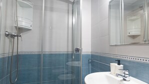 Ein Badezimmer mit Duschkabine aus Glas, einem weißen Waschbecken mit Spiegel darüber und blauen Fliesenwänden.