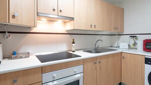 Eine moderne Küche mit Holzausbau, einer Edelstahlspüle, einem Einbauofen und einer Mikrowelle.