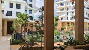Un moderno complejo de apartamentos con varios balcones, una piscina y jardines ajardinados.