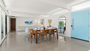 A modern dining area with a glass table, wooden chairs, and a light blue door.