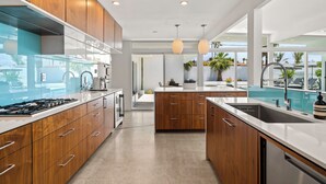 A modern kitchen with wooden cabinets, a stainless steel range, and a large island with a sink.