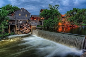 Experience the charm of a historic watermill, situated beside a serene water body, with a large wheel and multiple levels.