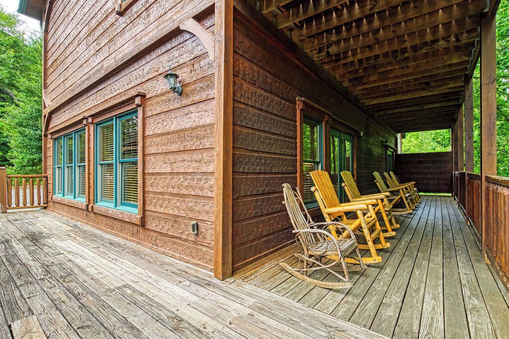 A wooden cabin with a porch and rocking chairs.