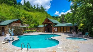 A pool area with two hot tubs, lounge chairs, and a stone patio. - It's 5 O'clock Somewhere: Hot Tub, Theater Room, Free Tickets, Game Room!!! (Gatlinburg)