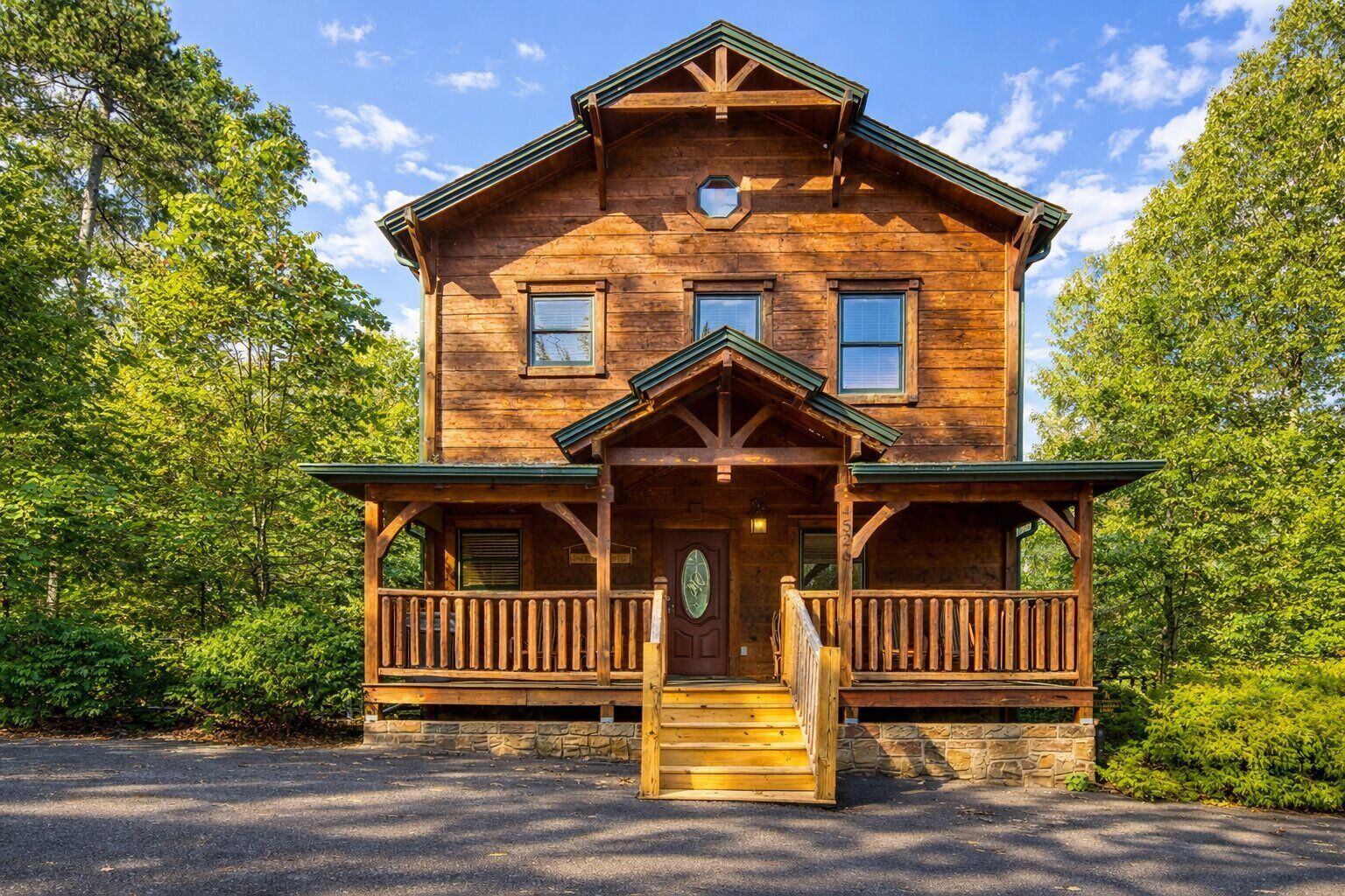 A wooden lodge with a porch, a front door, and a stone foundation.