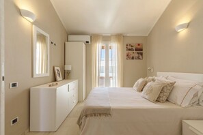 A bedroom with a bed, a dresser, a mirror, and a door leading to a balcony.
