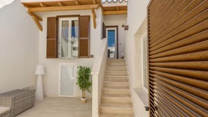 Una escalera que lleva a una puerta, una planta en maceta y una lámpara blanca en un pasillo.