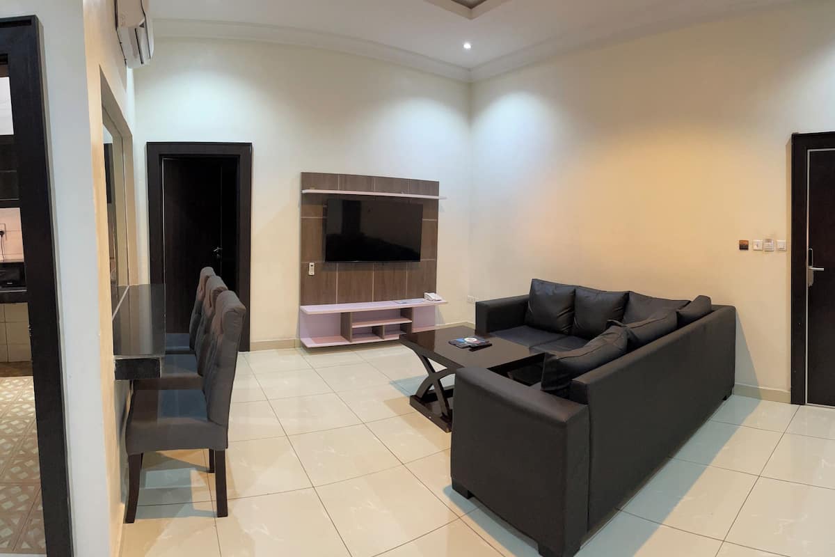 Un salon moderne avec un canapé foncé, une table basse et un téléviseur à écran plat fixé au mur.