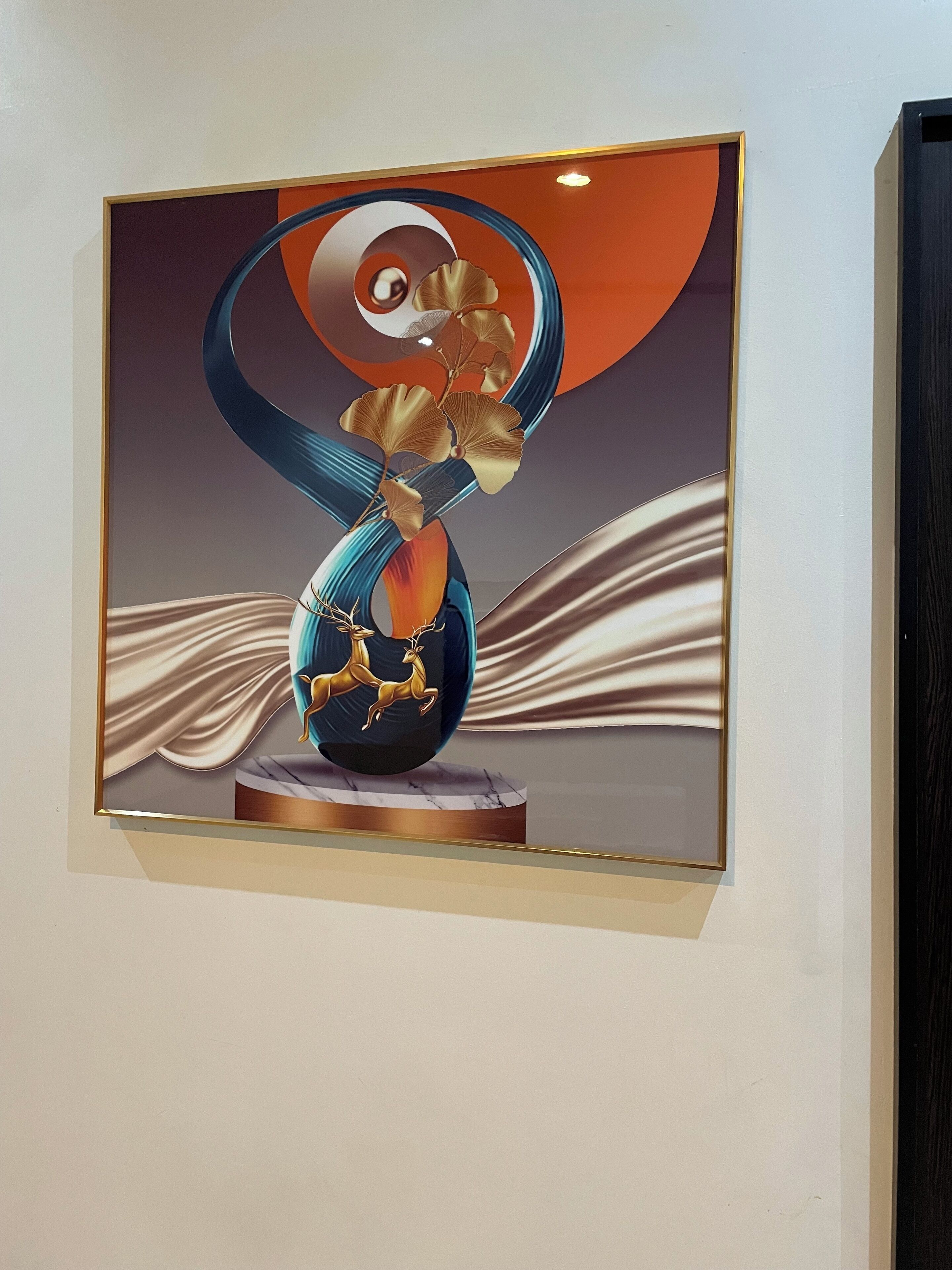 A framed artwork featuring a stylized vase with a golden ginkgo leaf and a deer, set against a backdrop of abstract shapes and a marble base.