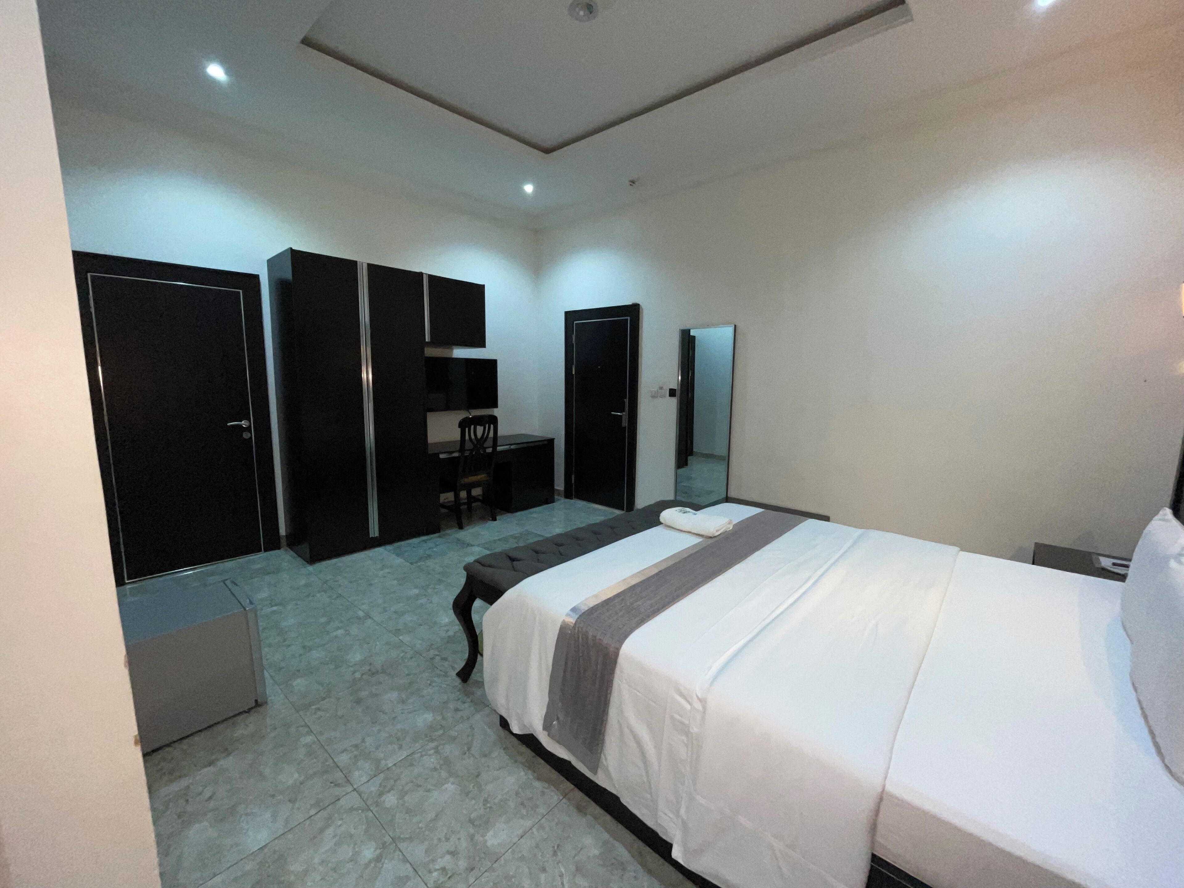 Una habitación de hotel con cama, escritorio, silla y armarios.