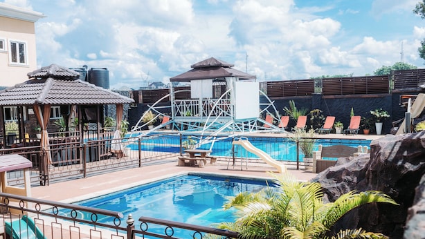A swimming pool with slides, a gazebo, and lounge chairs.