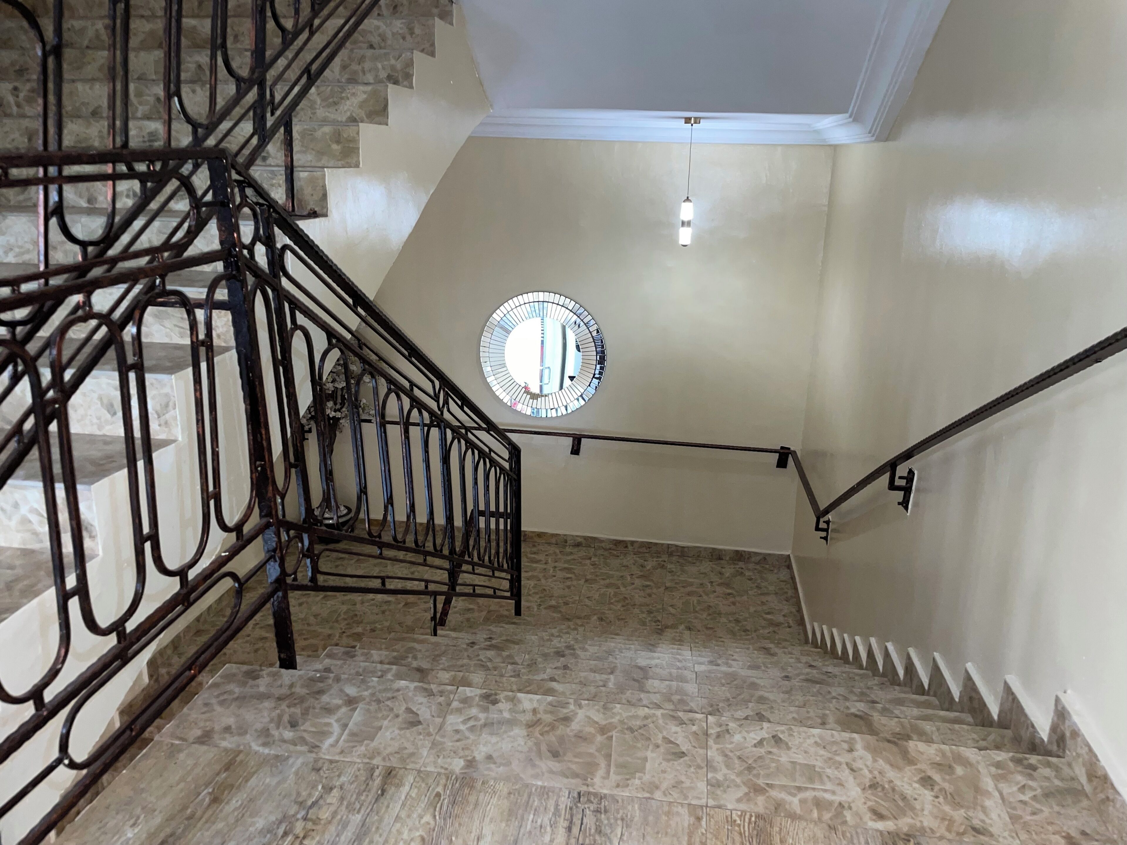 A staircase with a metal railing, a circular wall clock, and a hanging light fixture.