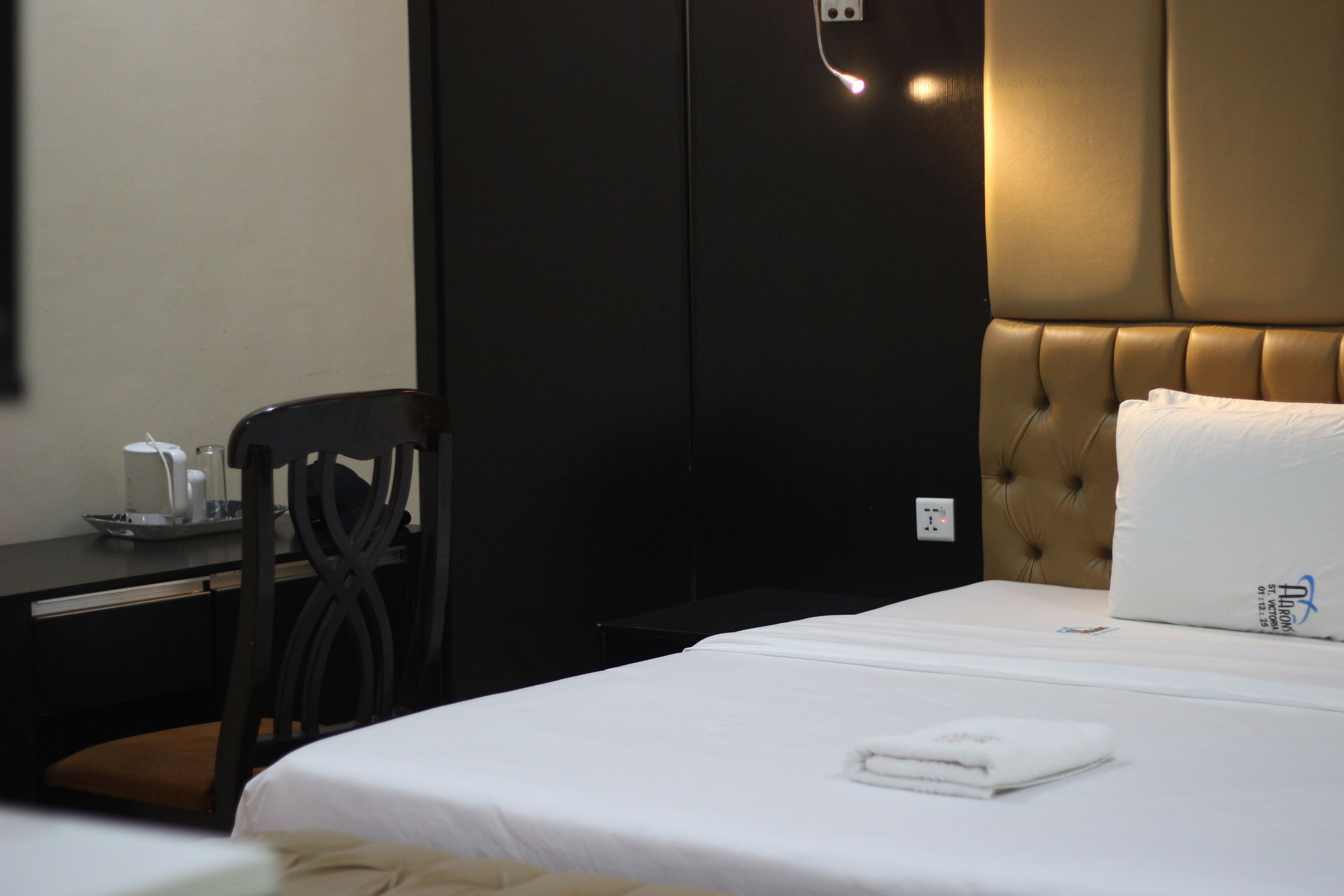 Une chambre d’hôtel équipée d’un lit, d’un bureau, d’une chaise et d’une prise électrique au mur.