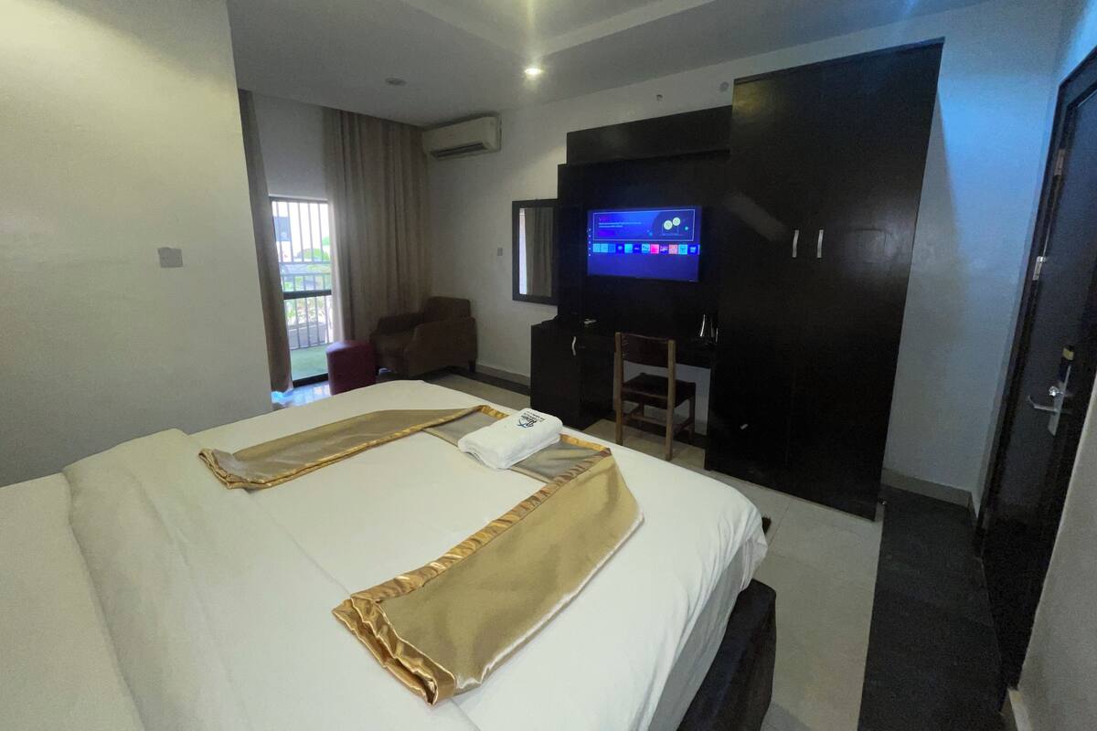Une chambre d’hôtel avec un lit, une télévision, un bureau et une chaise.