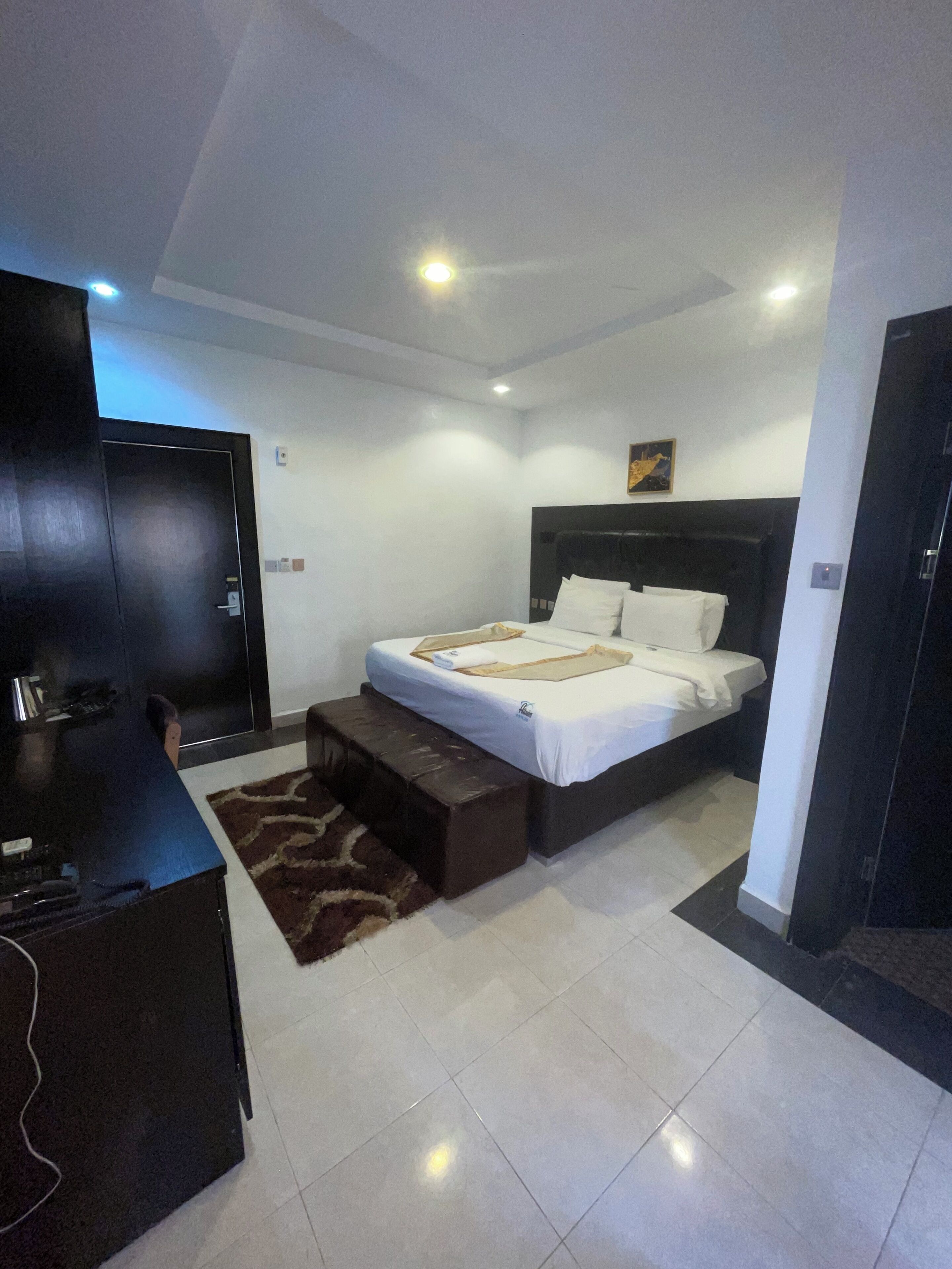 A modern hotel room with a large bed, a desk, and a flat-screen TV.