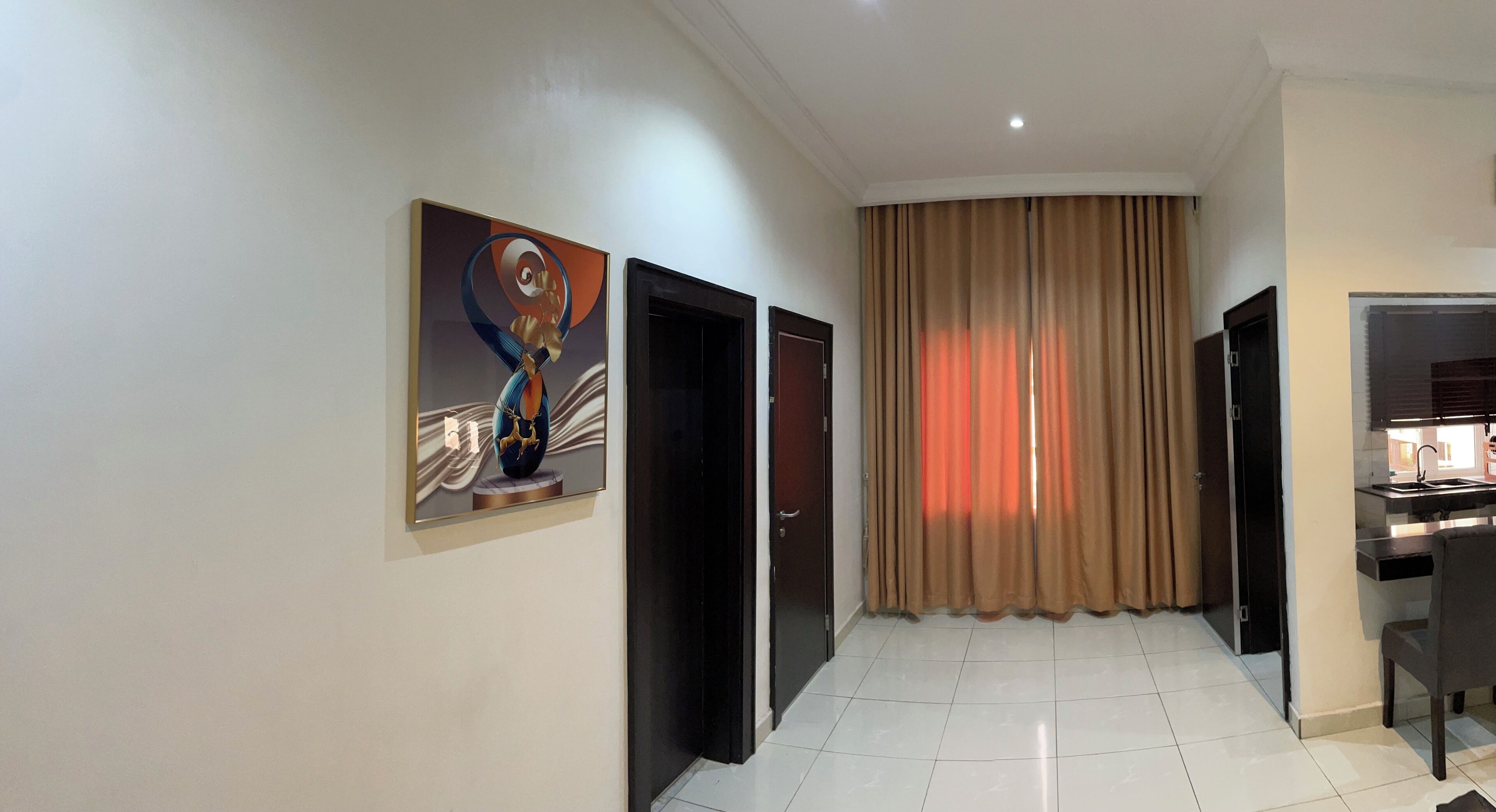 A hallway with a modern design, featuring a large abstract painting on the wall, a sliding door, and a view into a kitchen area.