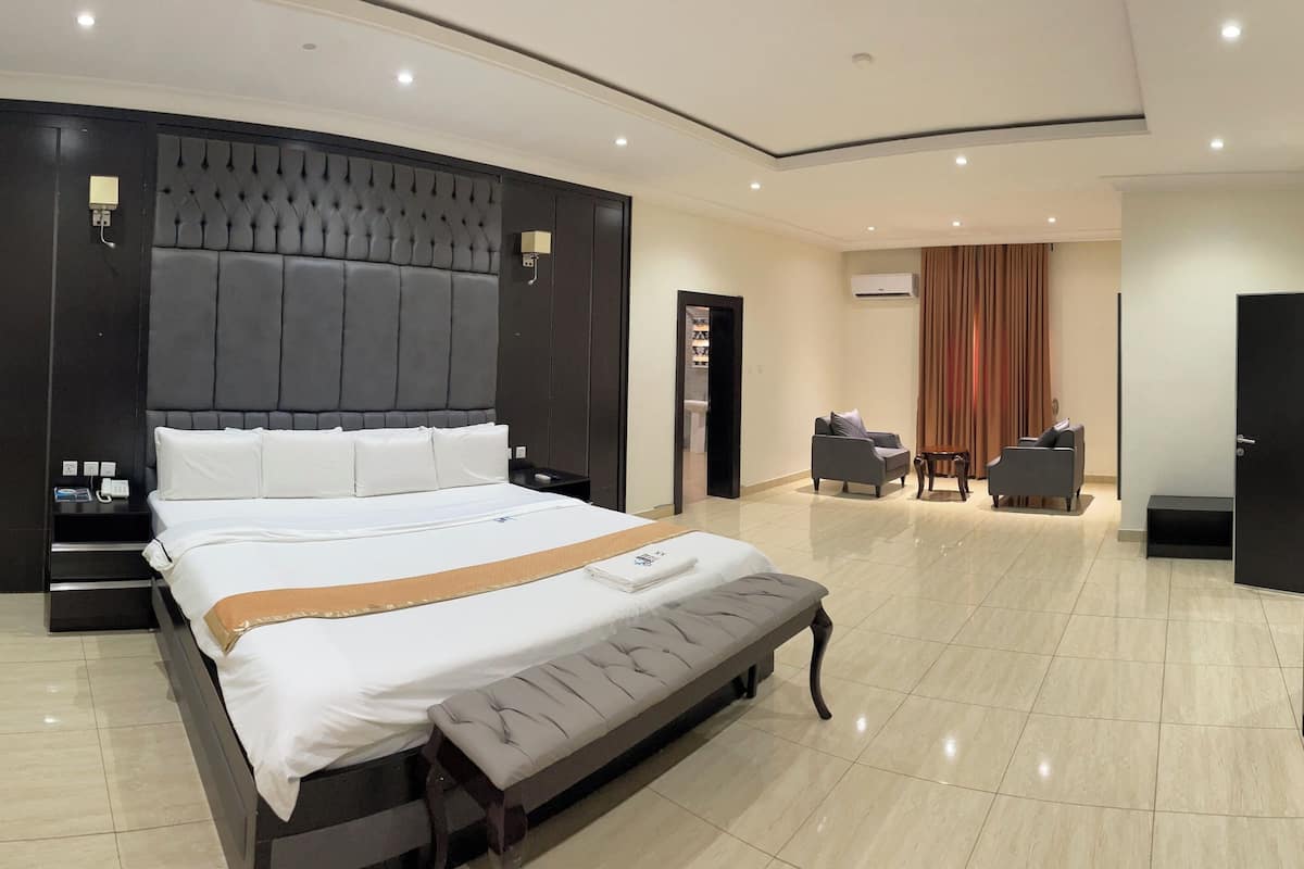 Une chambre d’hôtel moderne dotée d’un grand lit, d’une banquette, d’un bureau et d’un coin salon.