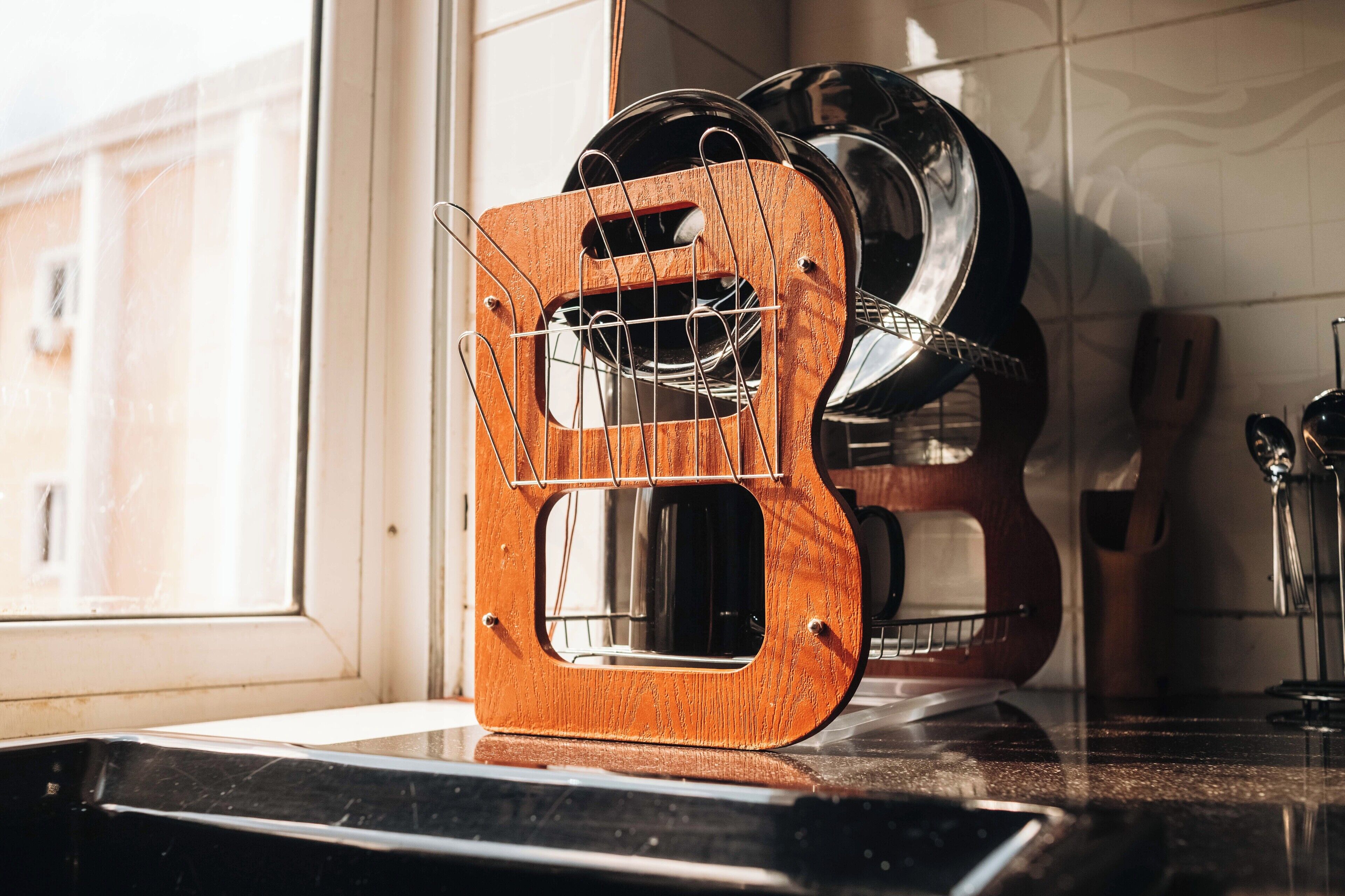Una encimera de cocina con un escurreplatos de madera que contiene varios platos y una tetera.