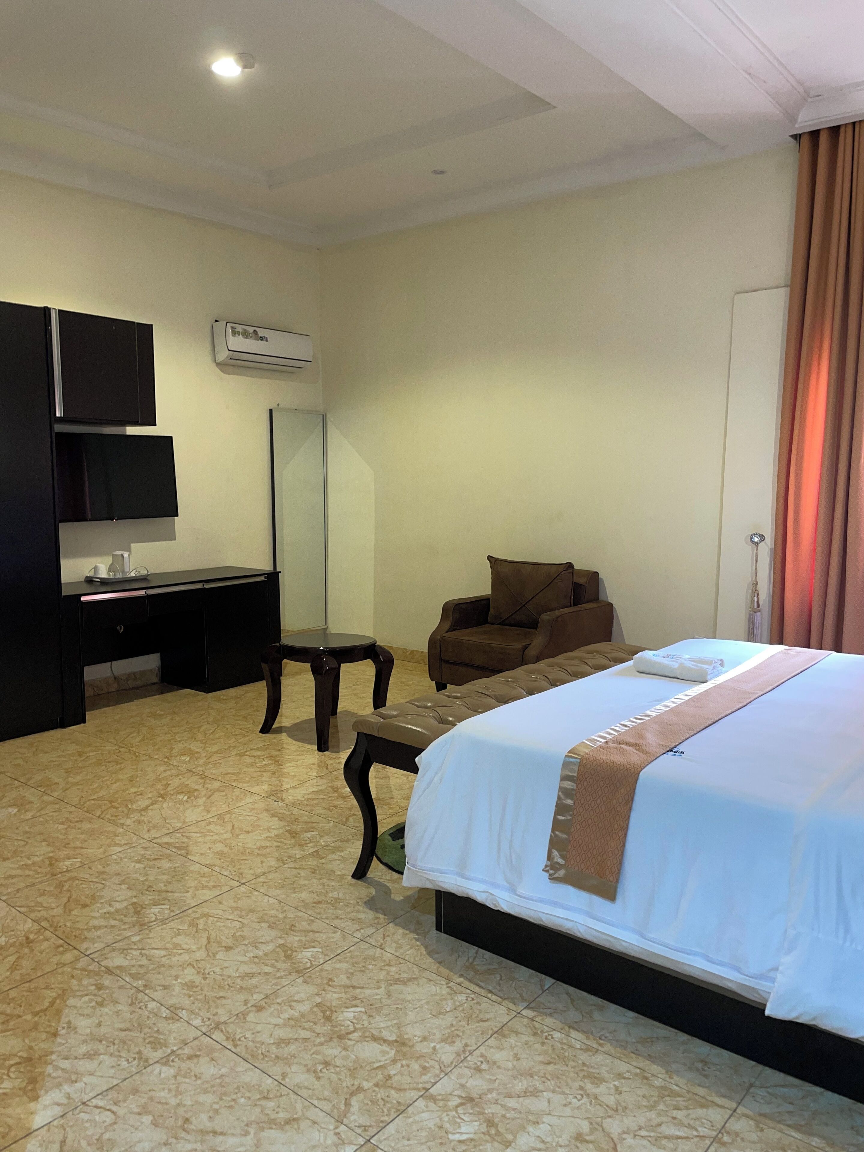 Una habitación de hotel con cama, escritorio, silla y televisor.