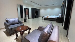A modern hotel room with a large bed, a sofa, a coffee table, and a mirror.