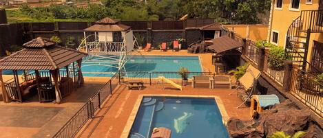 Relax by the resort pool surrounded by lush surroundings and a gazebo.
