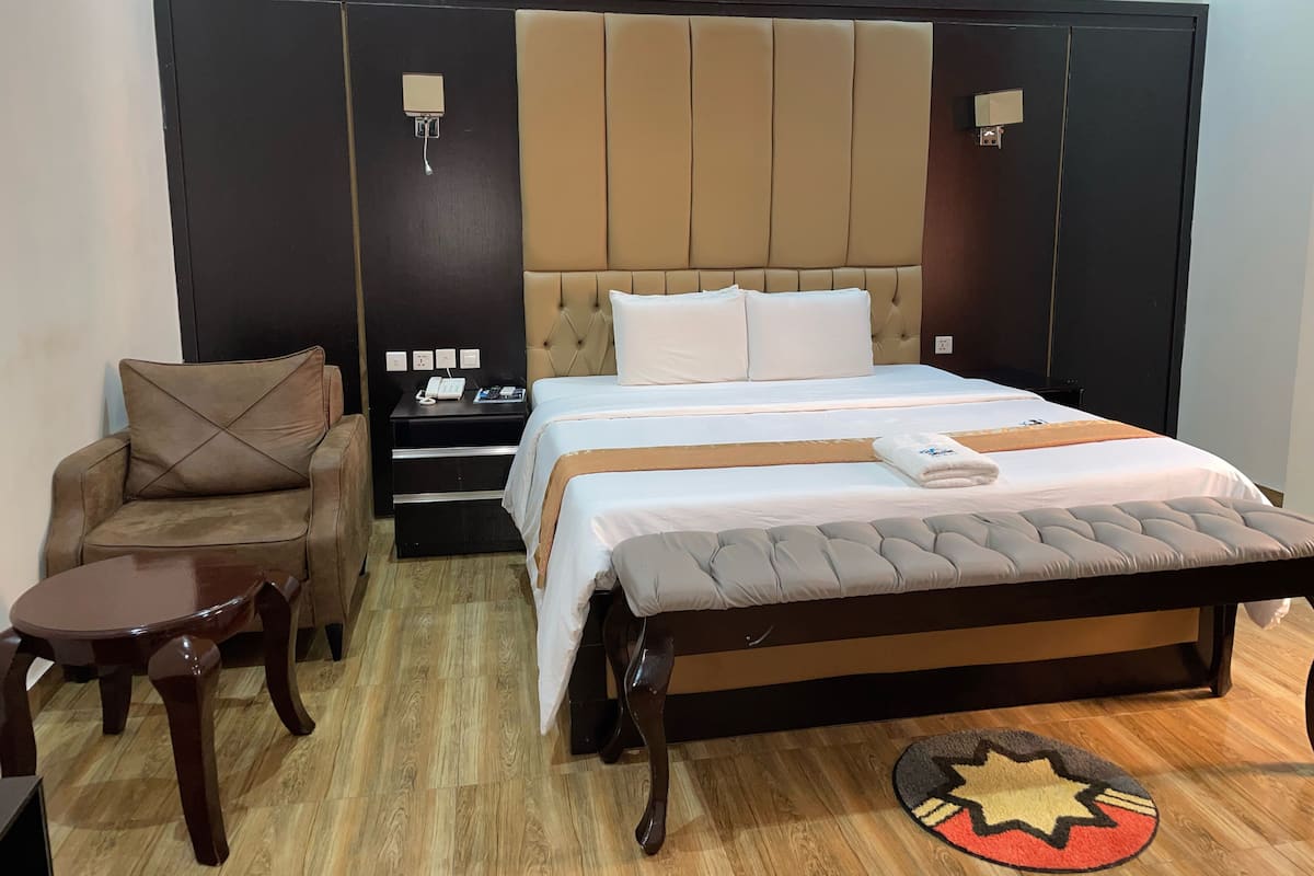 Une chambre d’hôtel avec un grand lit, une chaise, une table de chevet et une petite table.