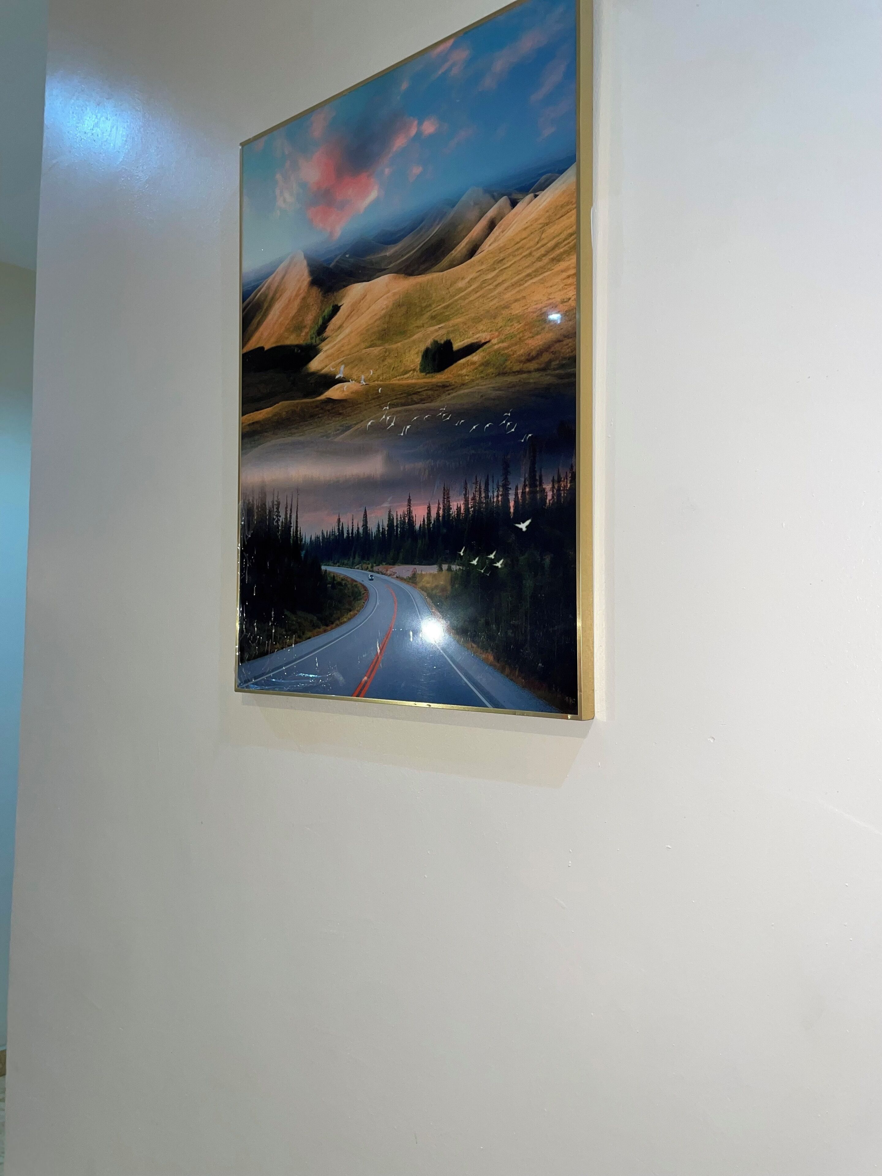Una pintura de un camino sinuoso que atraviesa un paisaje montañoso, con un bosque a un lado y un cielo despejado.