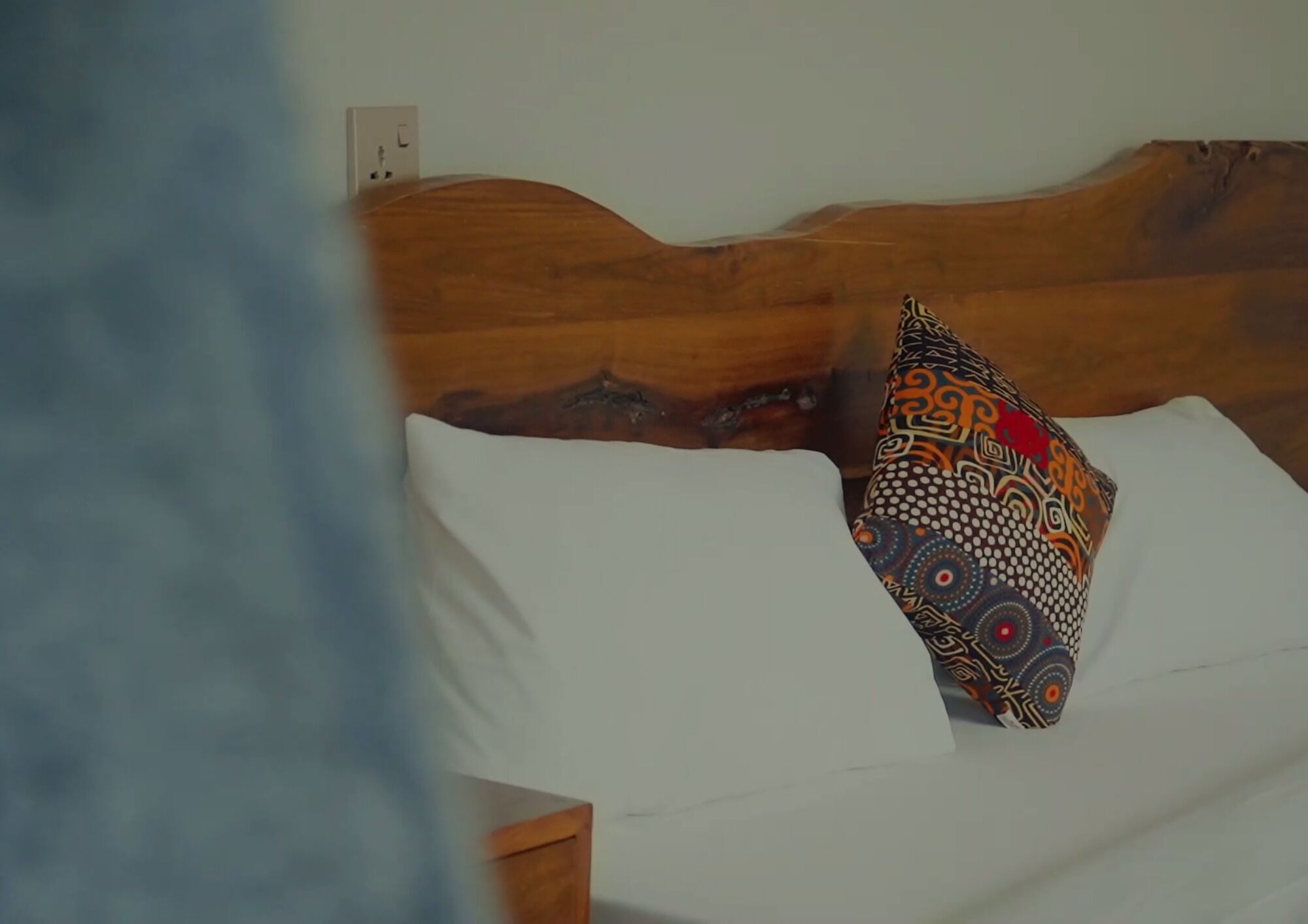 Una cama con cabecera de madera y almohada estampada.